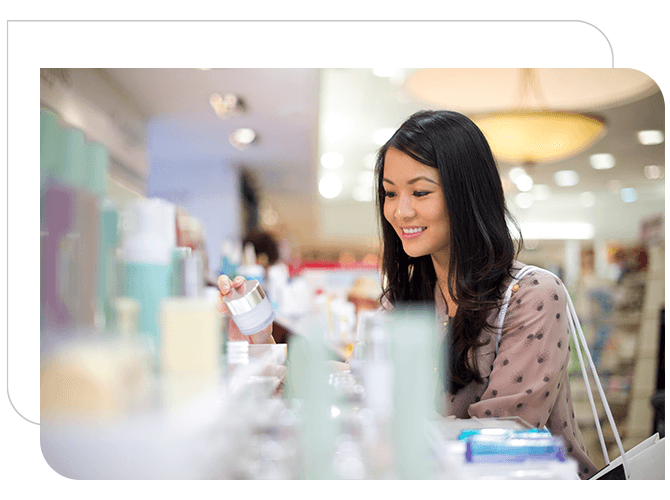 Woman looking at cosmetics in brightly lit department store.