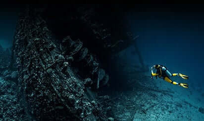 A person swimming in the deep sea with an oxygen cylinder.