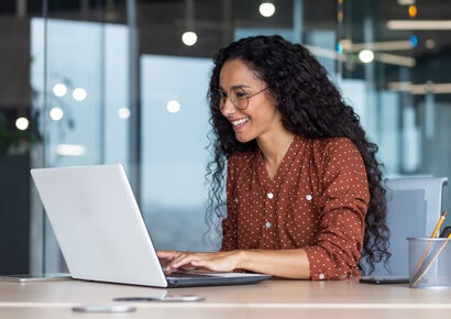 Hispanic woman on laptop in a  happy worksplace