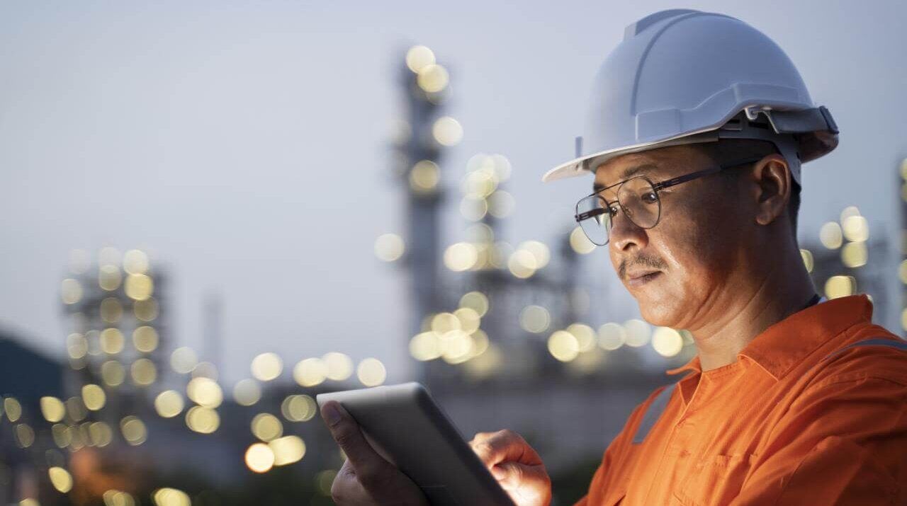 Engineer is collecting data of oil refinery through his laptop.