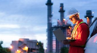 Engineer is collecting data of oil refinery through his laptop.