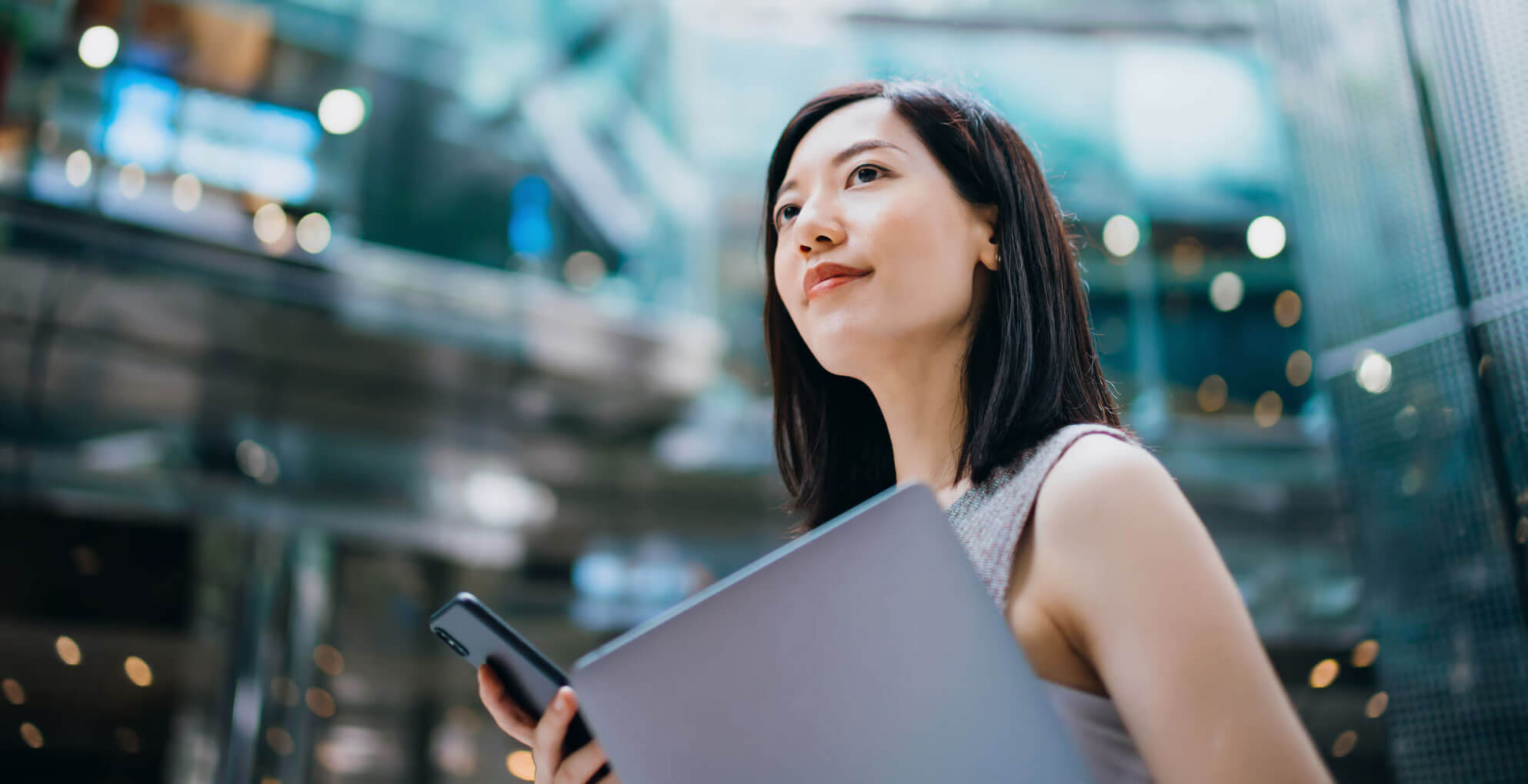 A Women Holding Laptop and Mobile is looking at sky