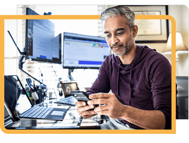 Man working at desk with multiple screens and devices.