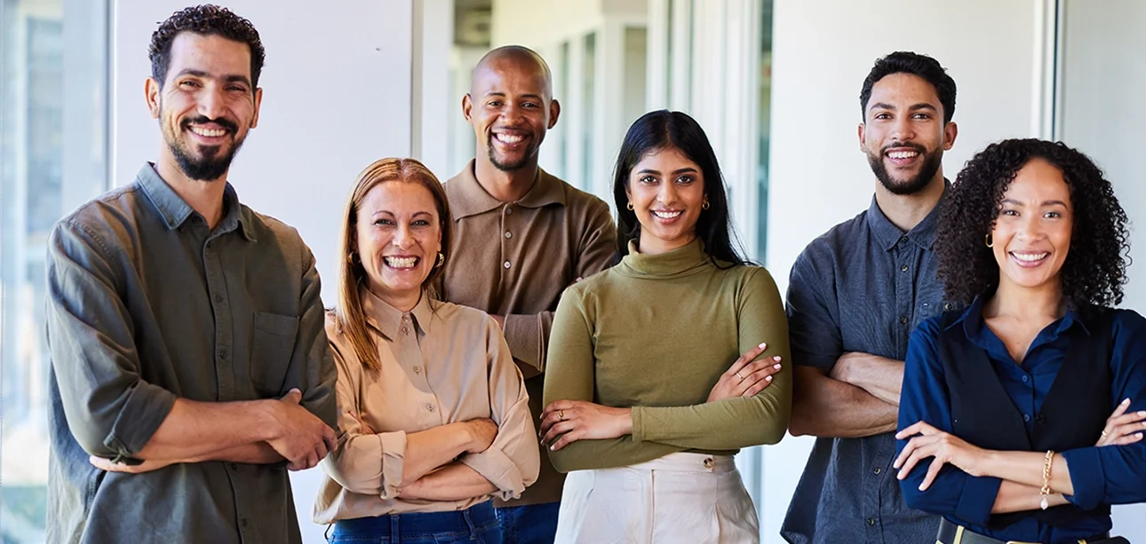 Diverse group of smiling businesspeople standing together in an office corridor, neutral colors