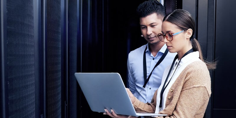 man and woman engineer looking at laptop in secure facility