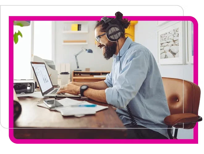 bearded man with headphone smiling at laptop
